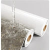 A roll of self-adhesive marble wallpaper being applied to a surface.