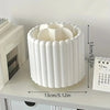 White rotating makeup brush organizer with removable compartments shown on a shelf.