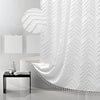 White boho waterproof shower curtain with a chevron pattern and tassels hanging in a modern bathroom setting.