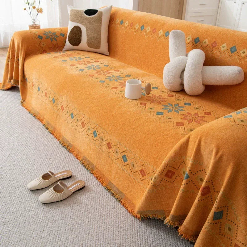 An orange bohemian jacquard sofa cover featuring geometric patterns and cream-colored throw pillows.