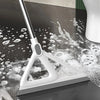 A white silicone squeegee broom is shown cleaning a dark floor surface with water and soap bubbles.