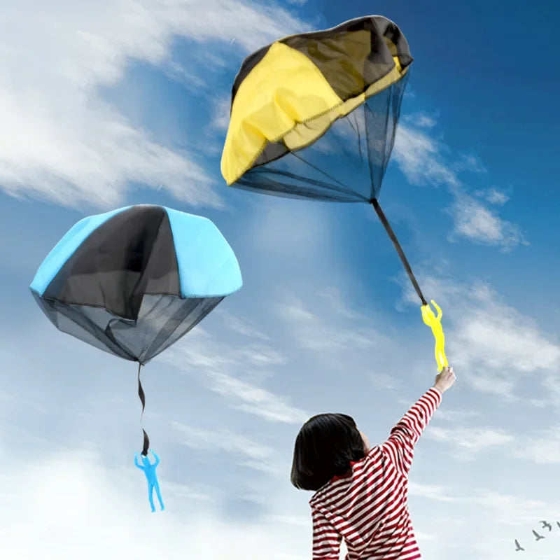 A child is flying a blue parachute toy with a mini soldier against a bright blue sky.