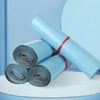 A stack of light blue poly mailer bags rolled up, resting on a white circular platform.