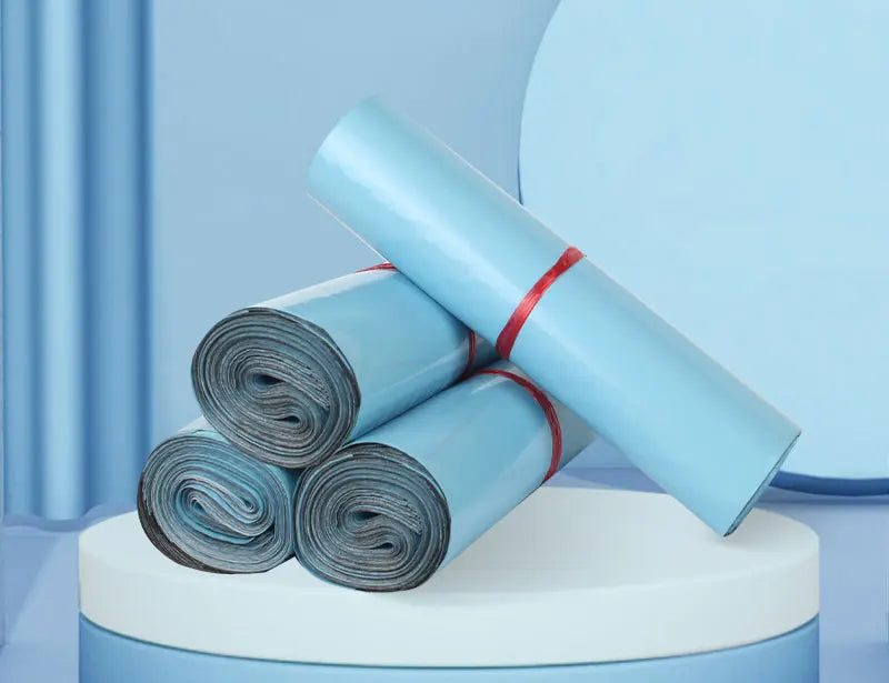 A stack of light blue poly mailer bags rolled up, resting on a white circular platform.