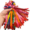 A hand is holding a bundle of colorful whistling flying party balloons in various bright colors.