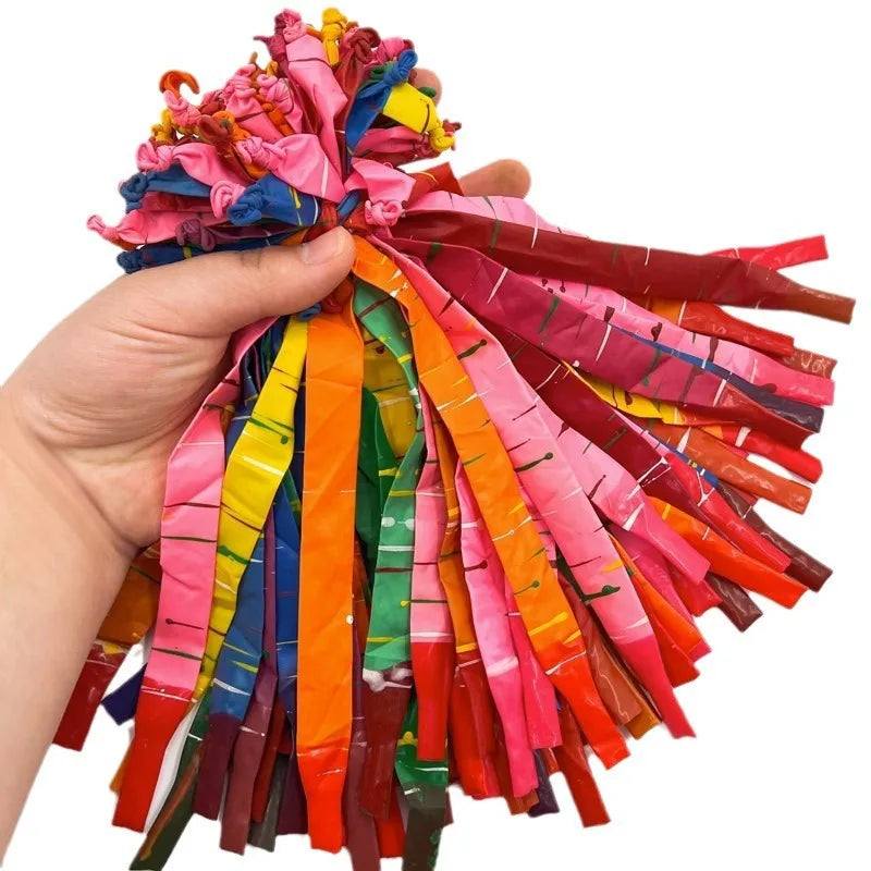 A hand is holding a bundle of colorful whistling flying party balloons in various bright colors.
