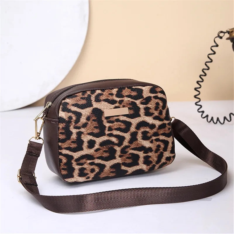 A brown leopard print crossbody bag with a dark brown strap resting on a white surface.