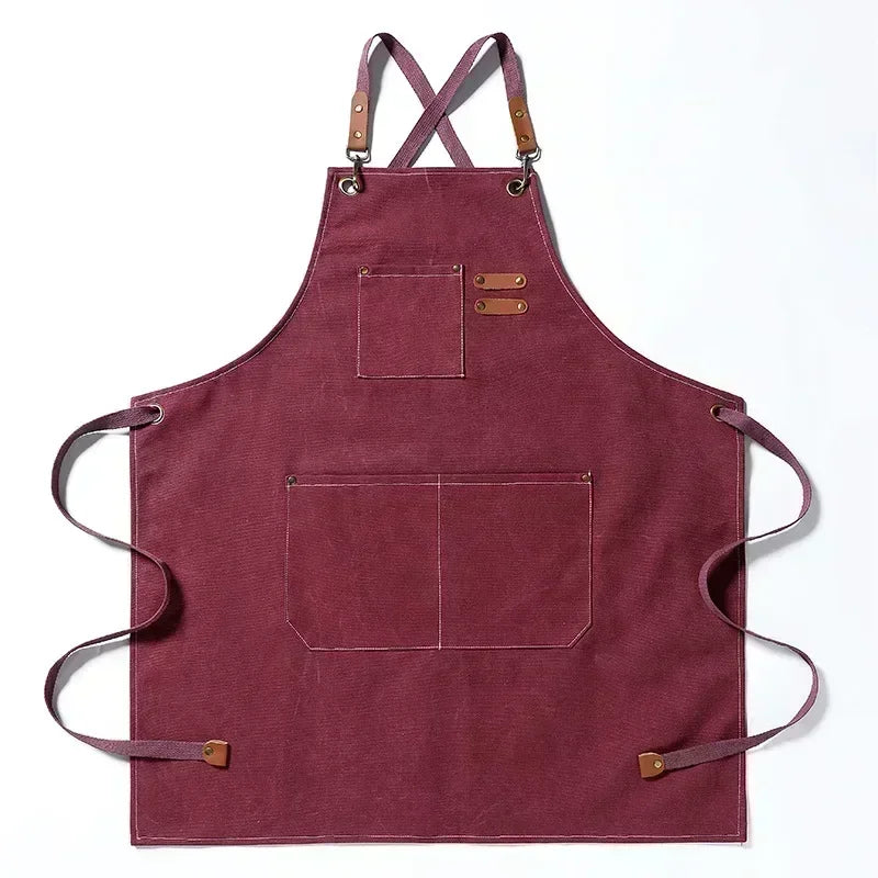 A deep maroon cotton canvas apron with cross-back straps and multiple patch pockets.