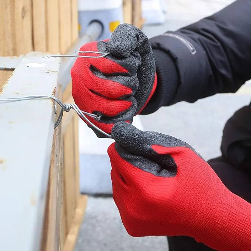 A hand wearing red work gloves is gripping a wire attached to a wooden structure.