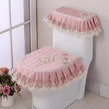 A pink antibacterial toilet seat cover set with a lace-edged cushion placed on a white toilet.