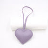 A small lavender heart-shaped PU leather keychain with a loop and a cotton peach charm.