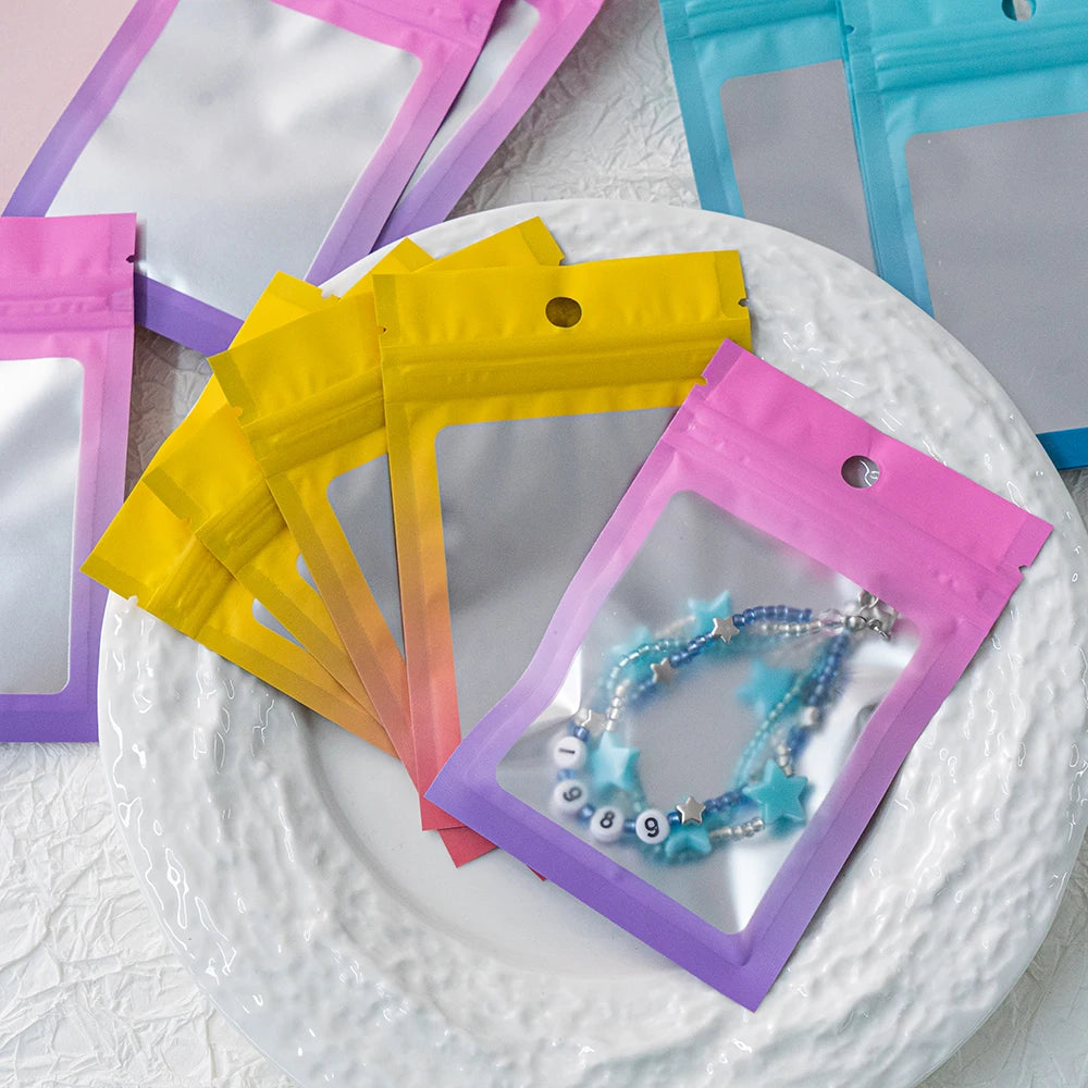 A collection of gradient colored resealable zipper pouches with clear windows are displayed on a white plate.