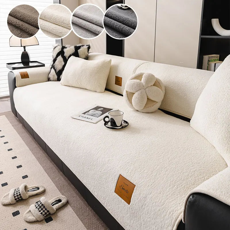 A cream-colored anti-slip lamb fleece sofa mat with decorative round cushions and a small leather accessory on a modern sofa.
