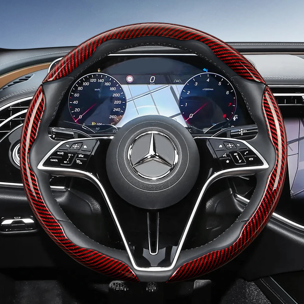 Close-up view of a black steering wheel with red carbon fiber texture covers and Mercedes-Benz instrument cluster.