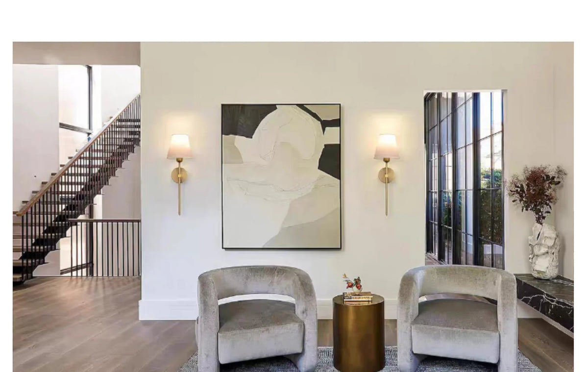 Two modern wall sconces with light bulbs mounted on a white wall in a contemporary interior.