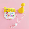 A yellow pet birthday party hat and bib set for cats and small dogs with a white cord.