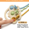 A hand holds a beige silicone bear teether with flexible keys and textured parts for baby play