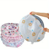 A white dust cover for electric fans is being held by a hand, showing decorative floral patterns.