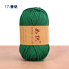 A ball of bright green cotton blend crochet yarn labeled in Chinese characters on a wooden surface.
