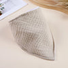 A beige, quilted soft cotton baby bib is shown on a light surface.