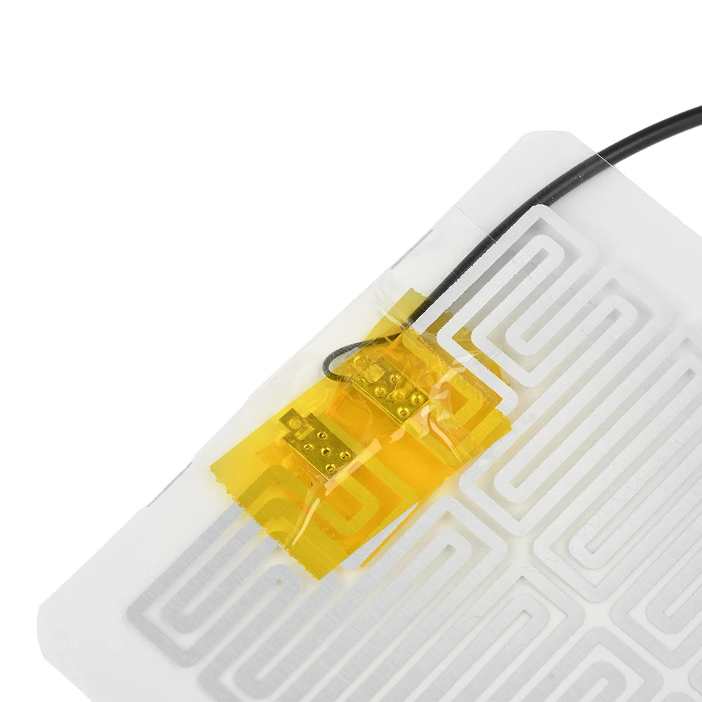 A yellow heating pad component with wires is placed on a white circuit board.