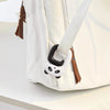 A white portable bag hook with a black panda charm and brown leather strap is shown on a light surface.