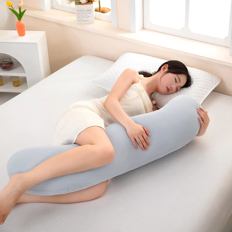 Una mujer yace en una cama blanca usando una almohada lateral de curva de ola ergonómica azul claro.