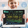 A smiling young boy holds a digital writing tablet displaying a colorful doodle of two hugging monsters.