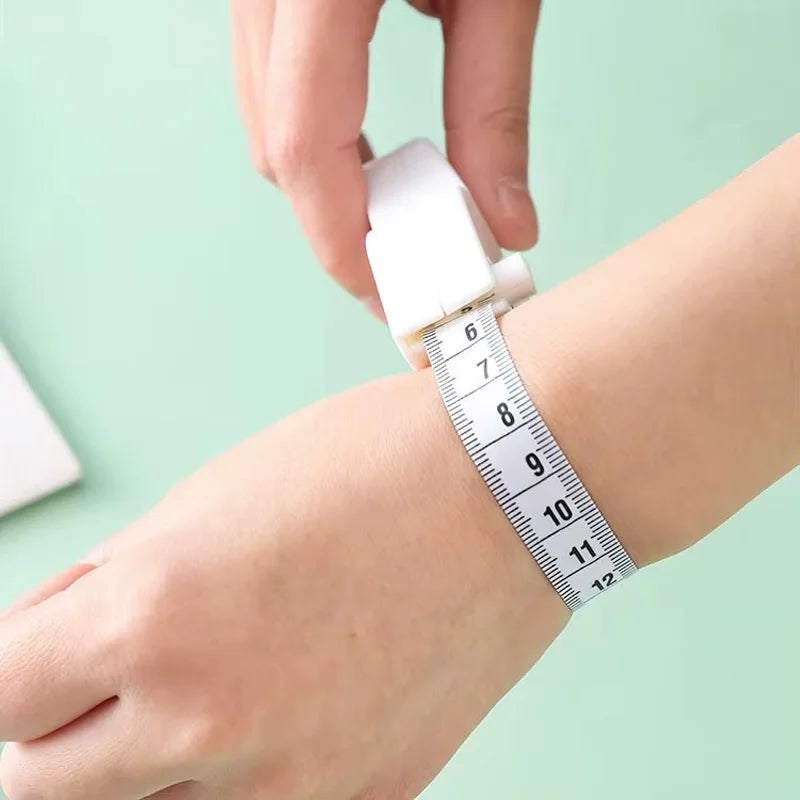 A hand is holding an automatic retractable body measuring tape wrapped around a wrist.