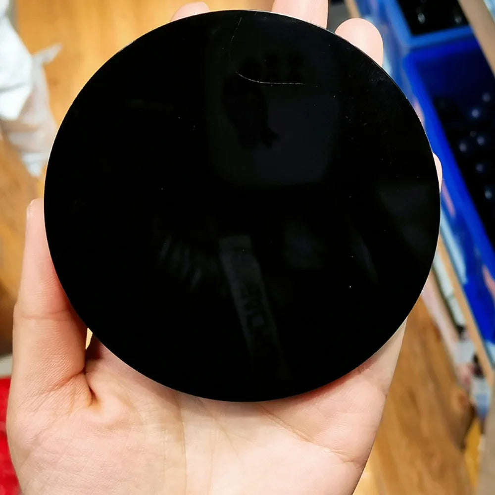 Une main tient un miroir de divination en obsidienne noire naturelle avec un support.