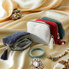 A collection of velvet jewelry organizer bags in various colors and textures, including a dark blue bag with tassels and gold