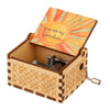 A vintage hand-cranked wooden music box with an orange sun design on the lid.
