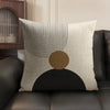A beige linen cushion cover featuring black geometric lines and a large brown circle on a dark background.