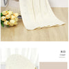 A cream-colored knit swaddle blanket displayed with yellow flower accents and a bunch of yellow tulips.