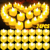 A heart-shaped arrangement of glowing yellow LED candles on a dark surface.