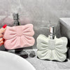 A pink ceramic pump dispenser for bathroom essentials is shown next to a white one on a gray countertop.
