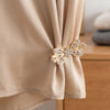 Gold rhinestone bowknot clothing clips securing a beige fabric garment.
