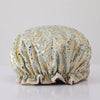 A reusable elastic shower cap for women in a light blue fabric with gold leaf pattern.