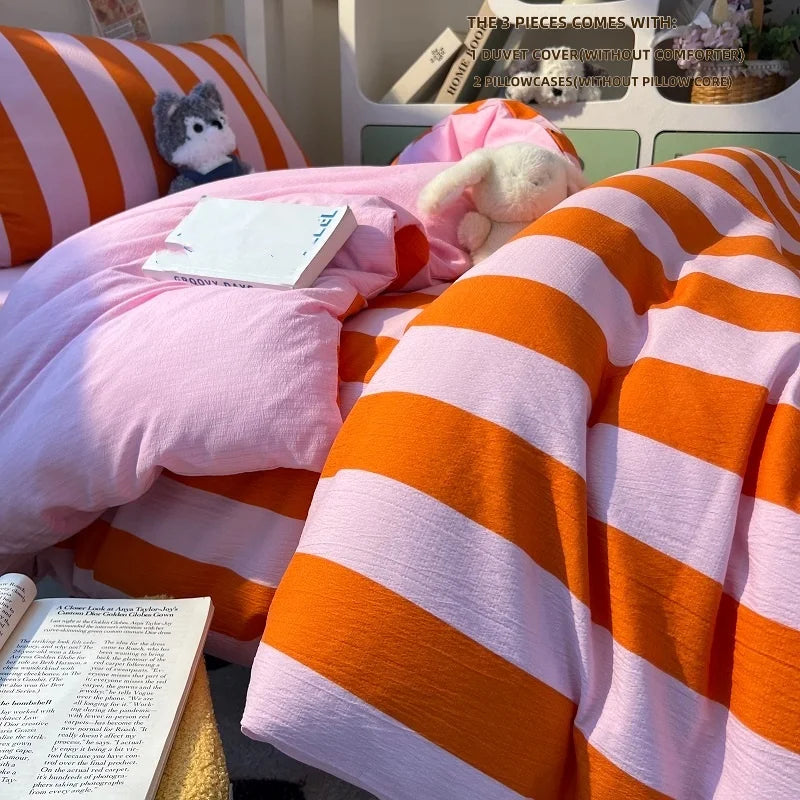 Orange and pink striped duvet cover set with pillowcases displayed on a bed.