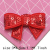 A set of five red sequin bow patches for DIY crafts displayed on a pink grid background.