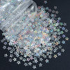A pile of shiny holographic star sequins scattered on a dark surface.
