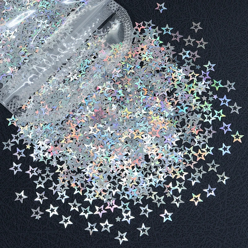 A pile of shiny holographic star sequins scattered on a dark surface.