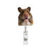 A brown hamster is pictured next to a silver badge reel with an alligator clip.