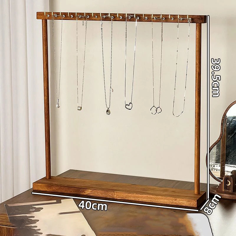 Organisateur de bijoux en bois massif avec plusieurs colliers d'argent suspendus à des crochets.