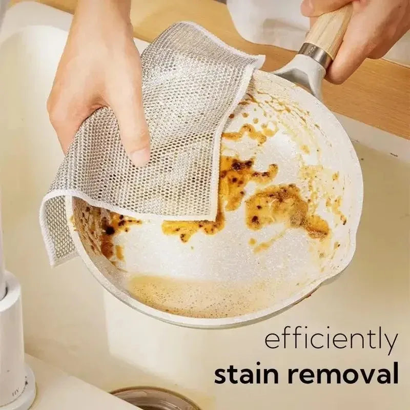 Hands are using a mesh cleaning cloth to remove stains from a non-stick pan.