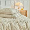 Beige, geprägte Blumen-Kopfteil-Duvetcover-Set auf einem Bett mit Lampe und goldenen Akzenten.