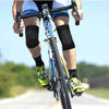 A person riding a bicycle wearing black knee pads and cycling gear on a road.