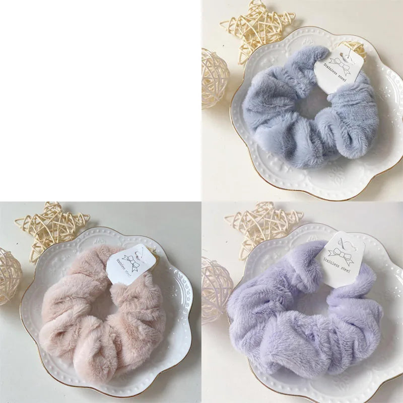 A close-up of soft, fluffy lavender and pink plush coil hair ties displayed on white ceramic plates.
