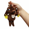 A hand is holding a brown plush chihuahua dog keychain pendant with yellow paws.