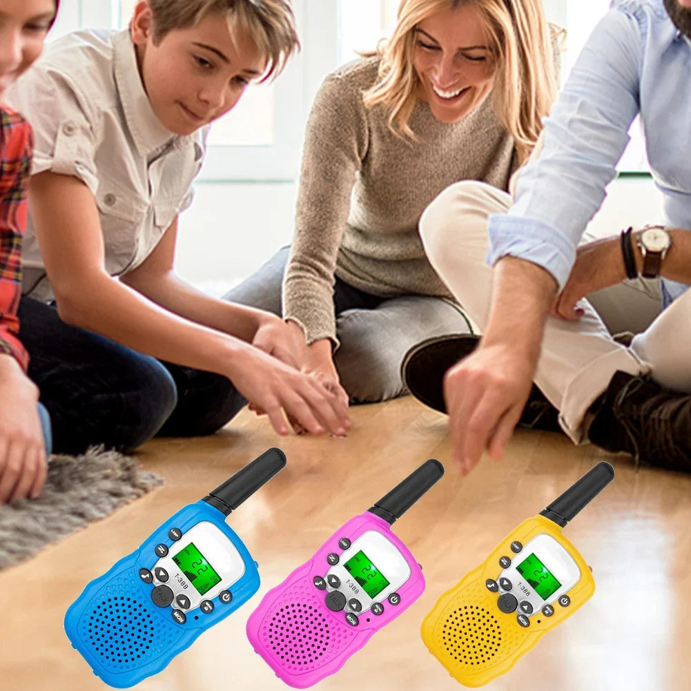 Three walkie talkie sets in blue, pink, and yellow are displayed on a wooden table with children nearby.